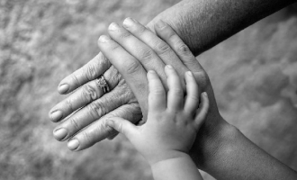 Three generations of hands stacked in a field