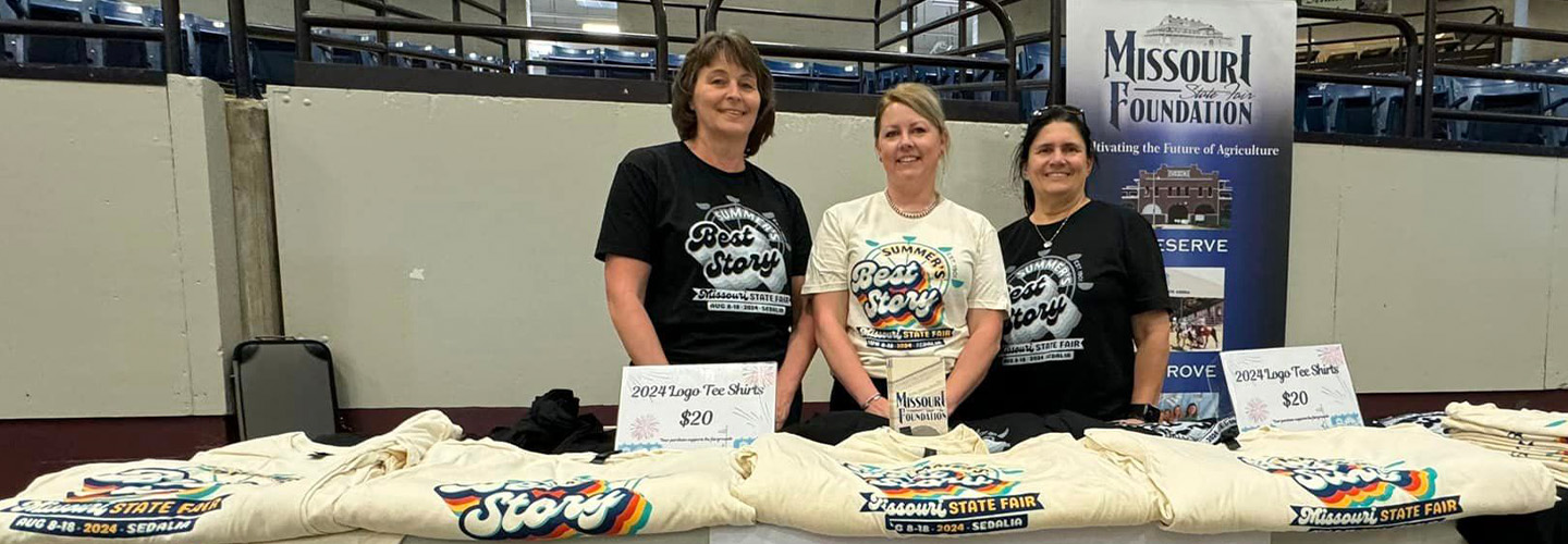 Three people selling souvenirs at a fair event